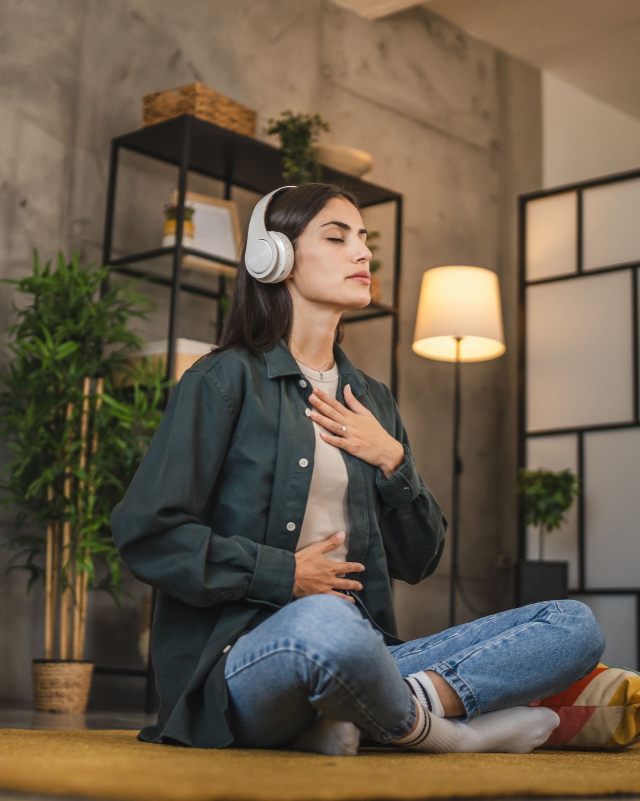 Adult woman sit on floor and have guided meditation on headphones